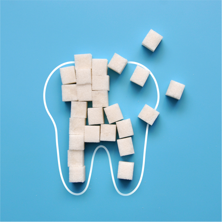 A tooth icon with a candy beside it, where the candy emits tiny bacteria or cavity spots toward the tooth — showing how sugar contributes indirectly to decay.
