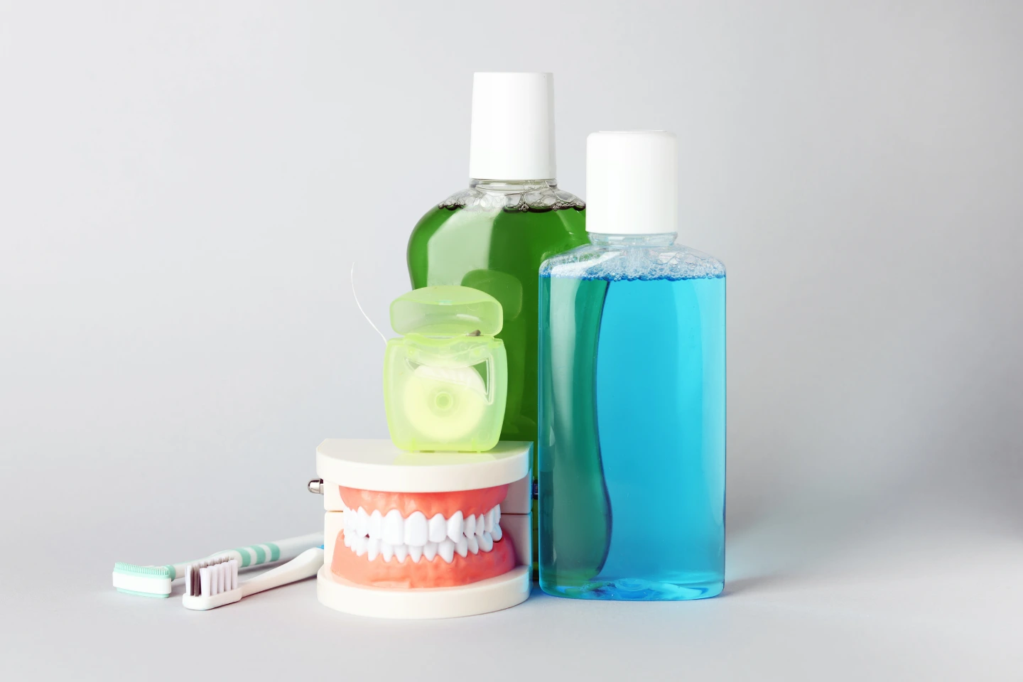 Dental hygiene tools including toothbrush, floss, mouthwash, and dental model—illustrating oral health care and preventive dental practices at IM Dentistry.