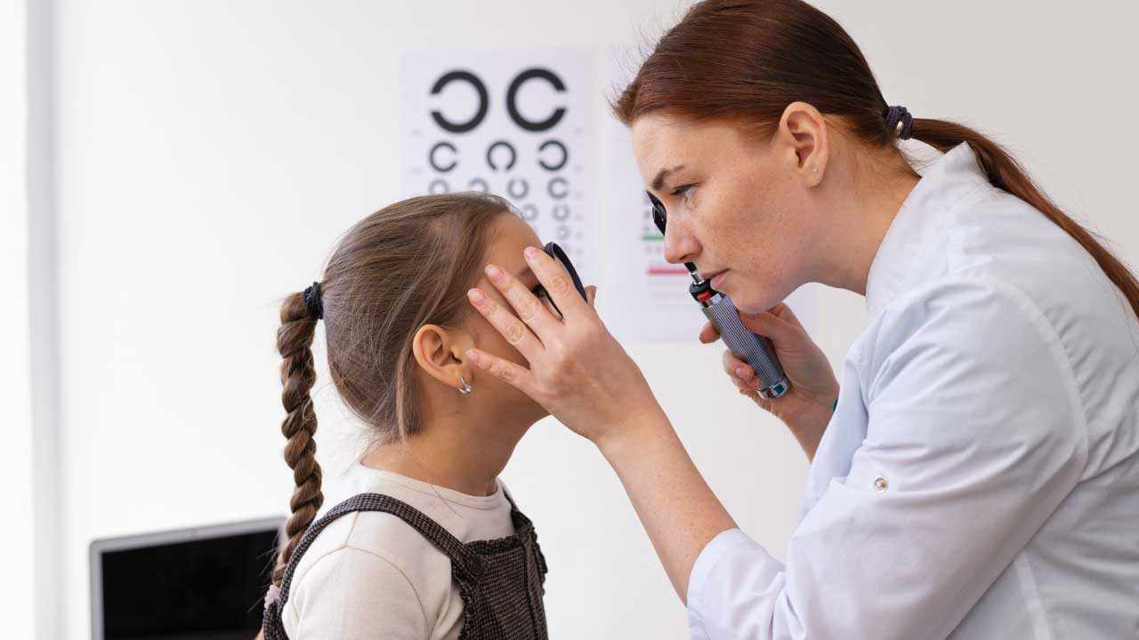Optometrist checking a young child’s eyes with specialized equipment