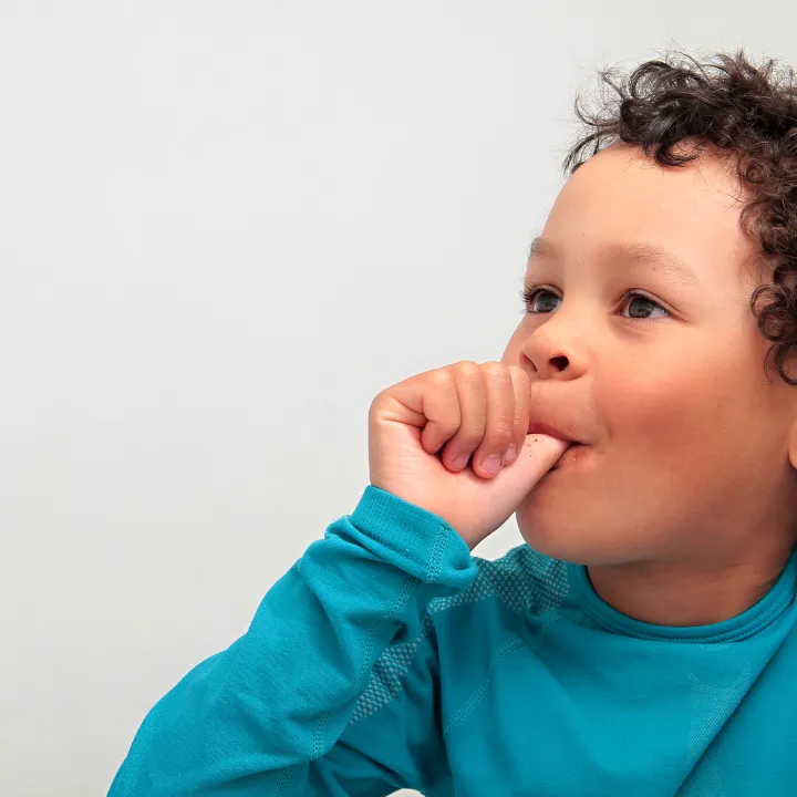 Child sucking thumb while an orthodontist explains its effects on teeth alignment