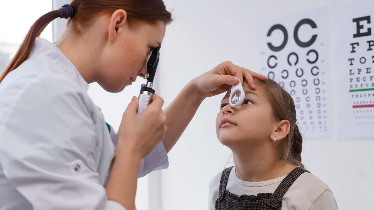 Doctor examining a young child during a pediatric eye examination to detect refractive errors.

