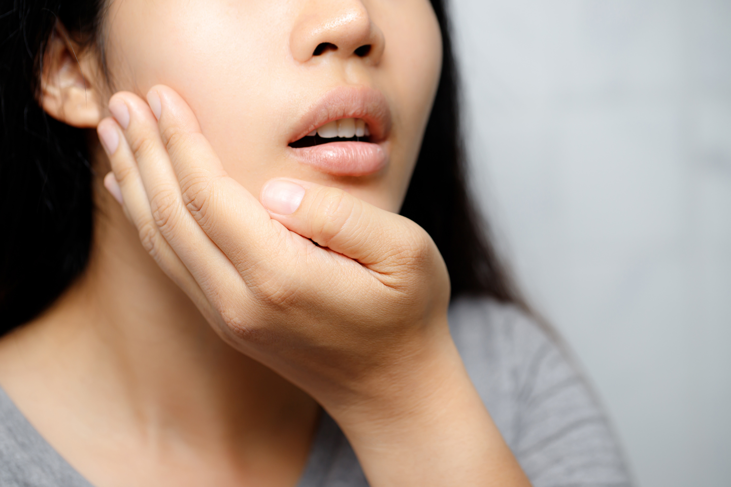 Person holding their jaw in pain at night, indicating nighttime toothache.