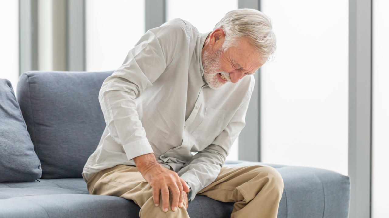 Person holding knee in pain during cold weather.